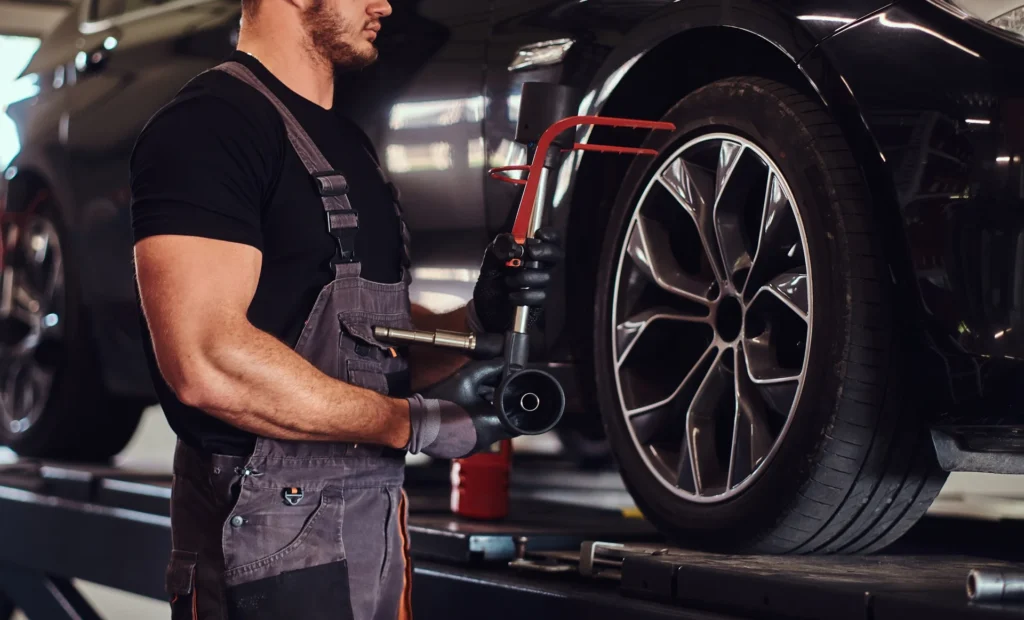 man is changing car wheel with special tool auto service